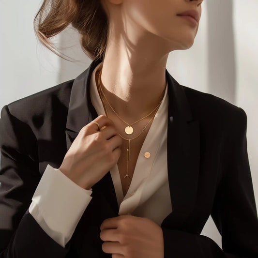 Elegante joyería de oro en Caracas, con una modelo luciendo un collar de disco y un colgante redondo pequeño, complementando un atuendo formal con blazer negro.