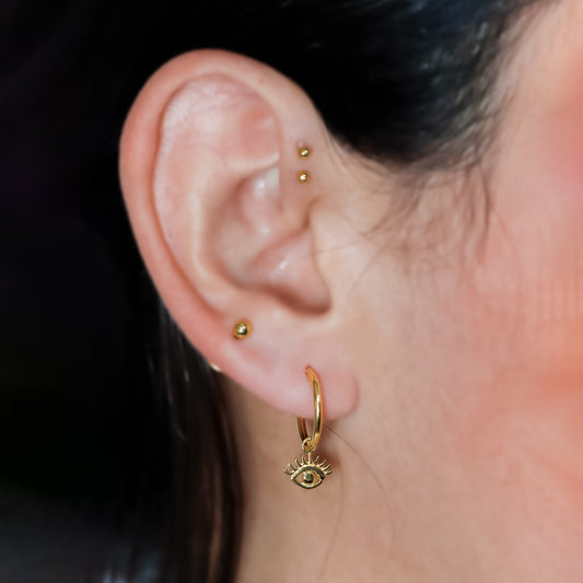 Estos elegantes aretes presentan un diseño Sin fin M con un Ojo turco en Oro 18K de alta calidad. Fabricados por Joyería Caracas, son una adición lujosa y exclusiva a tu colección. Además, cuentan con una garantía para toda la vida, asegurando su durabilidad.