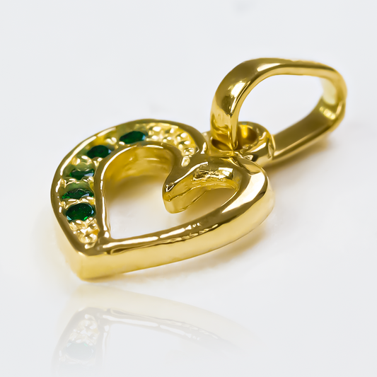 Dije Green heart cristal half JT de Joyería Caracas es el epitome de elegancia y lujo. Con su acabado en Oro 18K y cristal verde, cuenta con garantía de por vida. 