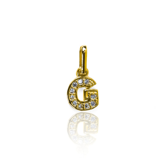 Este elegante dije de letra G está hecho de oro 18K y cuenta con un delicado cristal mini JT. Con su diseño exclusivo de Joyería Caracas y garantía para toda la vida, este dije es una pieza de lujo que nunca pasará de moda. Delicado, sofisticado y eterno, es perfecto para aquellos que buscan un estilo único.