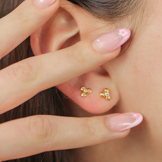 Oreja de mujer con topito en forma de flor de loto acanalada en oro amarillo de 18 quilates con cristal de color blanco, hechos en Joyería Caracas. 