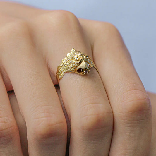 Dedo con anillo de hombre en forma de águila en oro amarillo de 18k, con 2 cristales de color verde en los ojos y 1 cristal blanco en la punta del pico hecho en Joyería Caracas. 