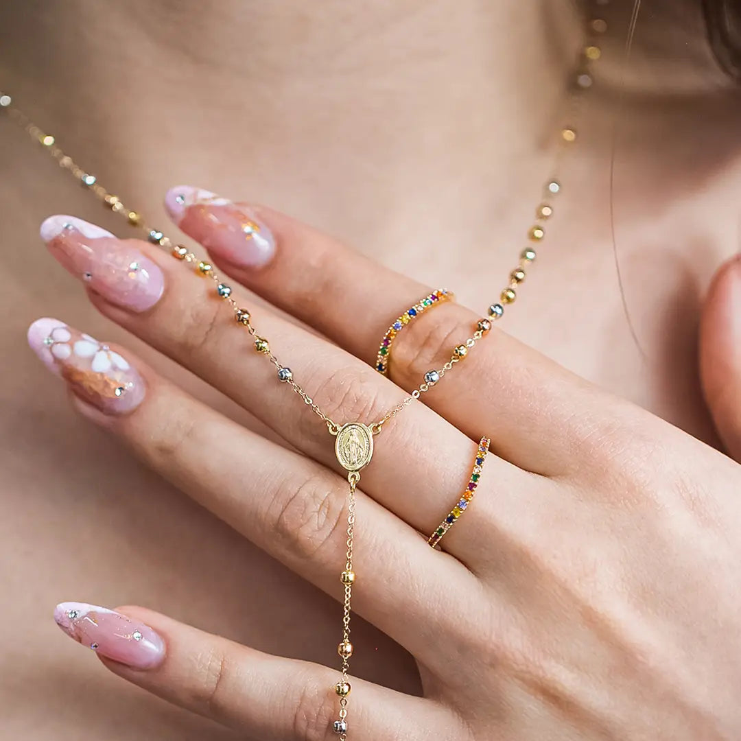 Mano de mujer con anillo en oro amarillo de 18 quilates con cristales de distintos colores, hecho en Joyería Caracas. 