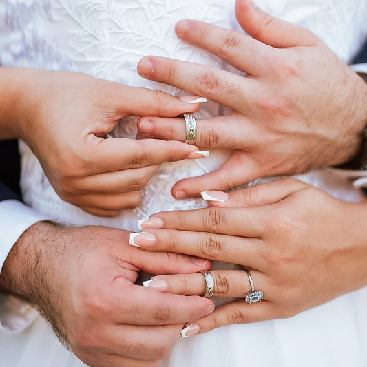 Manos de hombre y mujer en matrimonio sosteniendo cada argolla en oro amarillo de 18k, la cual tiene texturas que lucen cada argolla. 