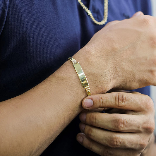 Mano de hombre con pulsera esclava lisa en oro amarillo de 18 quilates y tejido bismarck hecho en Joyería Caracas.