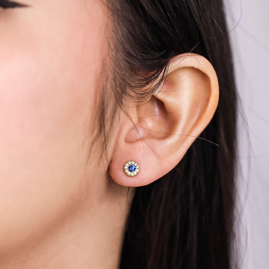 Oreja con topito circular en oro amarillo de 18k, centro de cristal en color azul y a su alrededor cristales de color blanco hecho en la Joyería Caracas.