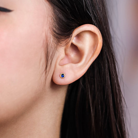 Oreja con topito en forma de dona biselado en oro amarillo de 18k con cristal de color azul de la Joyería Caracas.