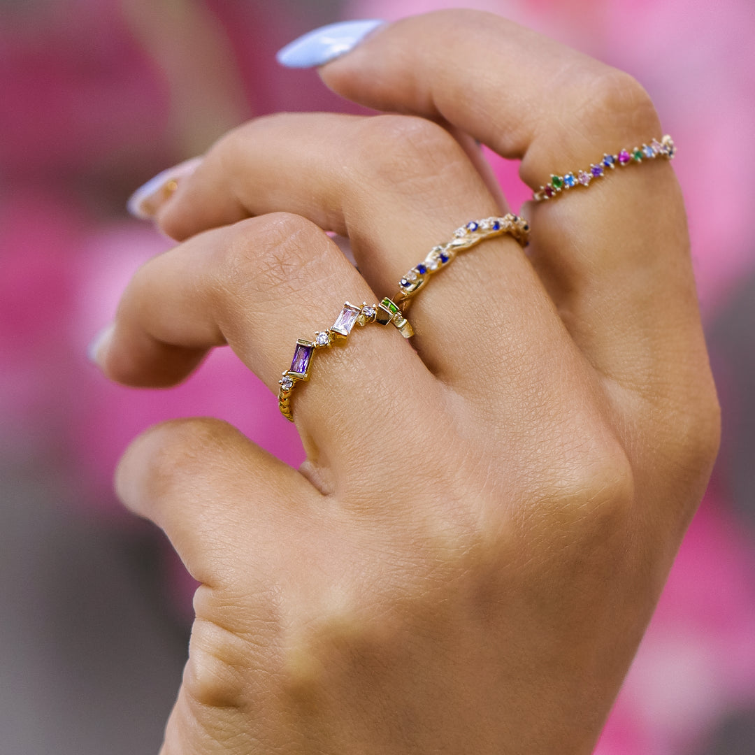 Mano de mujer con anillo en oro amarillo de 18 quilates con cristales de distintos colores ubicados asimétricamente, hecho en Joyería Caracas. 