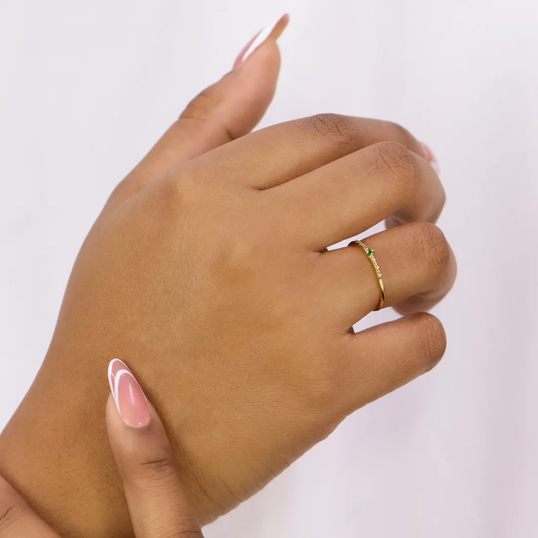 Mano de mujer con anillo en oro amarillo de 18 quilates con cristales de color blanco y verde, hecho en Joyería Caracas. 