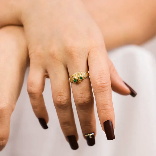 Mano de mujer con anillo en forma de Búho en oro amarillo de 18 quilates con 2 cristales de color verde, hecho en Joyería Caracas.  