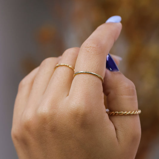 Mano de mujer usando anillo en forma de círculos pequeños en oro amarillo de 18 quilates, hecho en Joyería Caracas. 