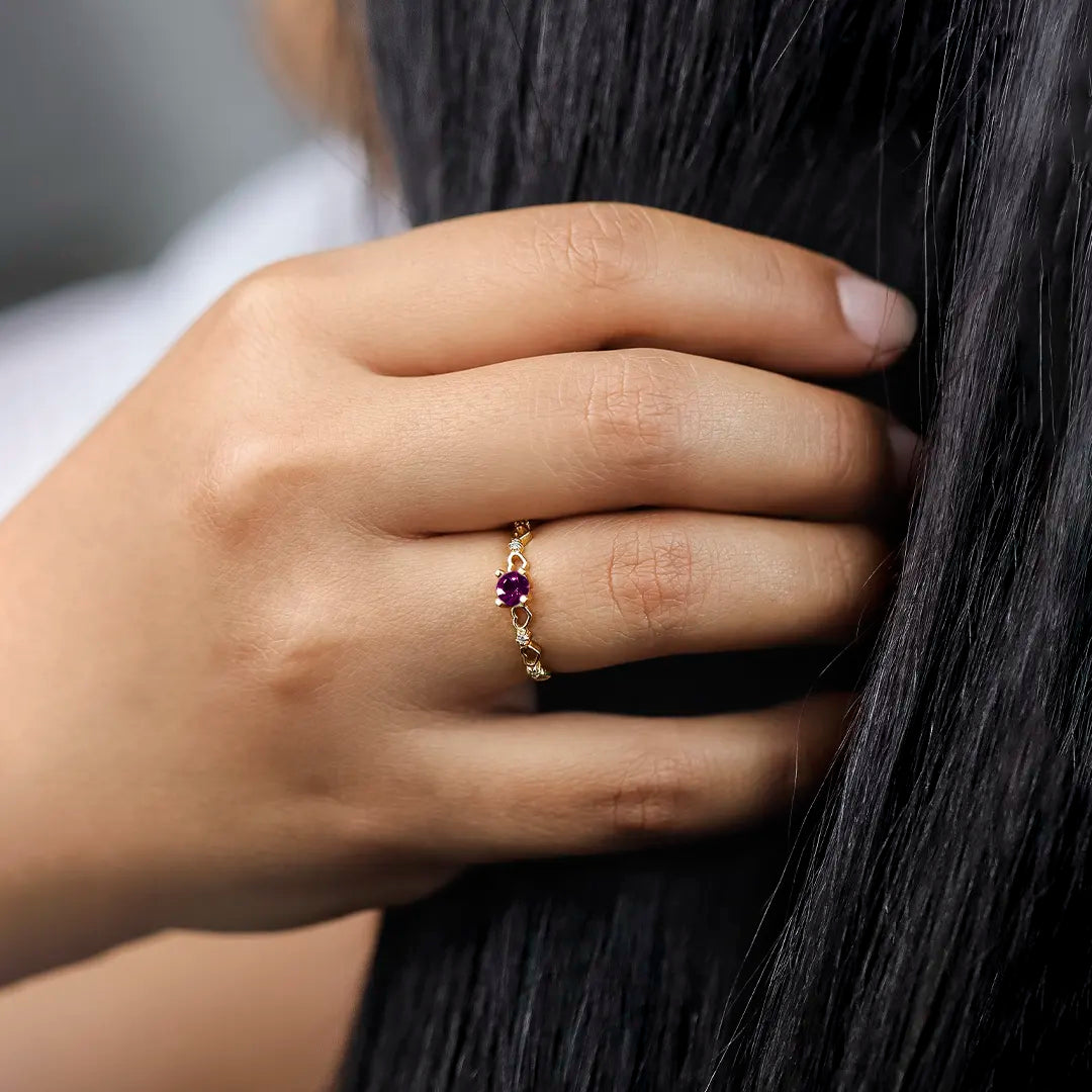 Mano de mujer con anillo en oro amarillo de 18 quilates, con Rubí natural y cristales de color blanco, hecho en Joyería Caracas. 