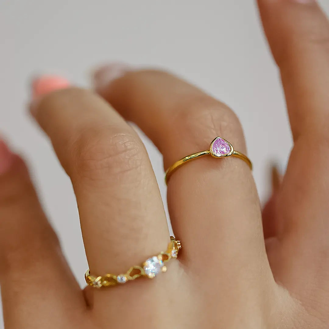 Mano de mujer usando anillo con corazón en el centro en oro amarillo de 18 quilates y diamante en forma de corazón en color blanco, hecho en Joyería Caracas. 