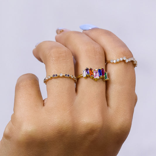 Mano de mujer con anillo en oro amarillo de 18 quilates con cristales en corte baguette de distintos colores, hecho en Joyería Caracas. 