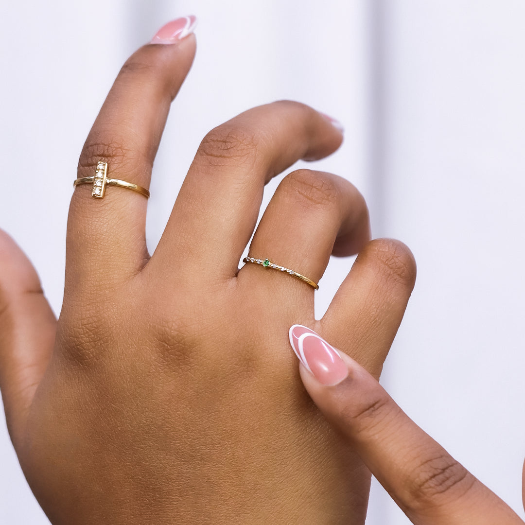 Mano de mujer con anillo en oro amarillo de 18 quilates con cristales de color blanco y verde, hecho en Joyería Caracas. 