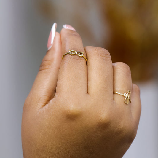 Mano de mujer usando anillo con alas en oro amarillo de 18 quilates, hecho en Joyería Caracas. 