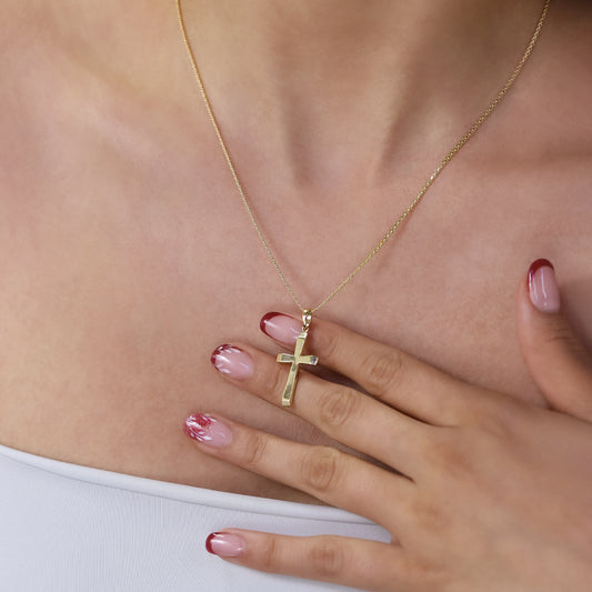 Cuello de mujer con dije de cruz en oro amarillo de 18 quilates, hecho en Joyería Caracas. 