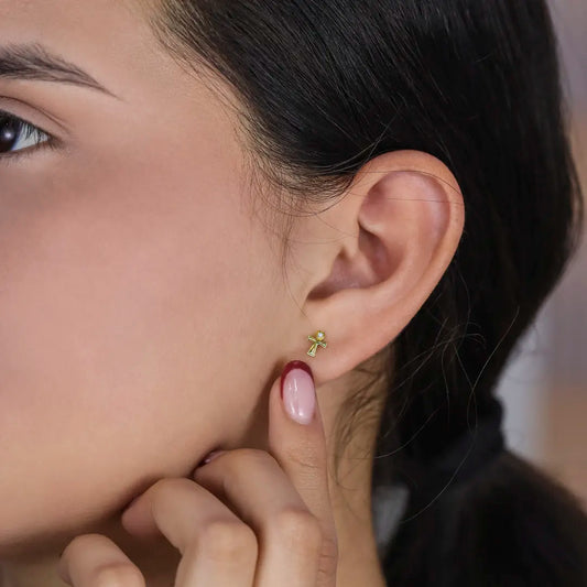 Oreja de mujer con topito en forma de cruz- ángel en oro amarillo de 18 quilates con un cristal de color blanco, hechos en Joyería Caracas. 