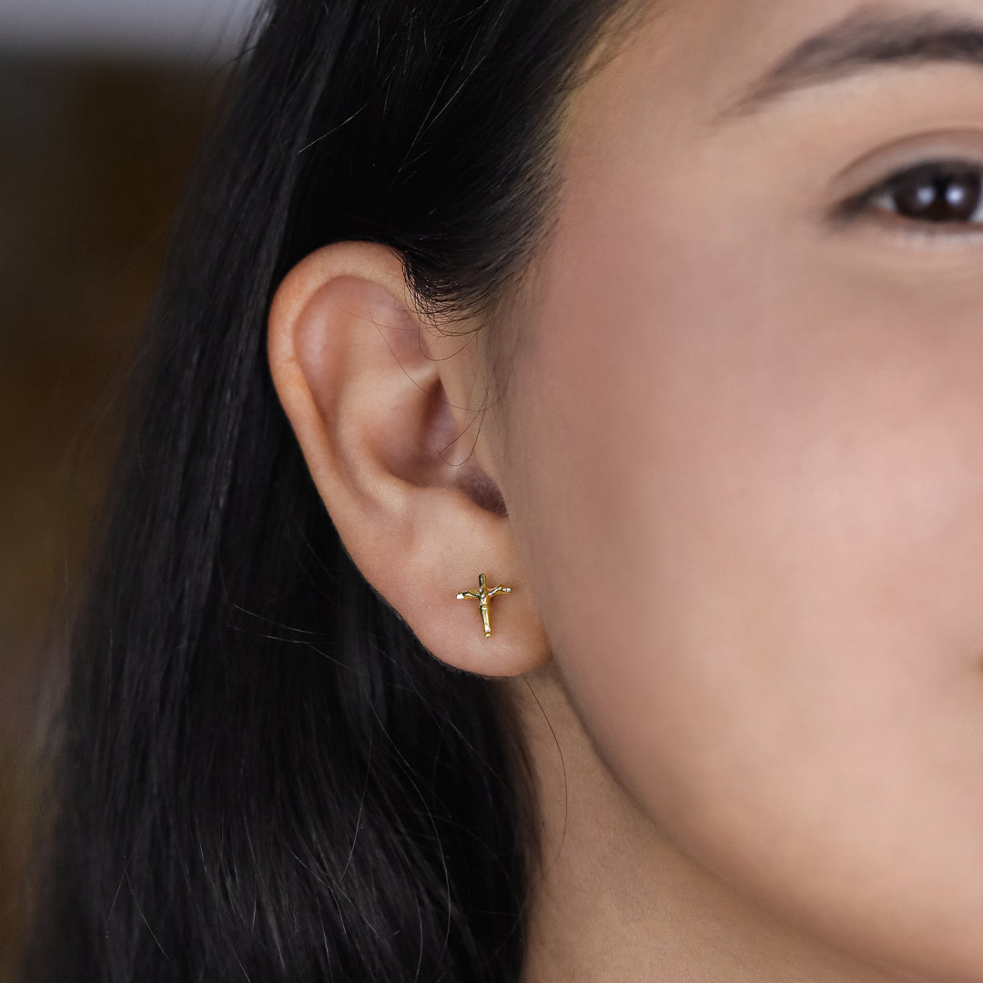 Oreja de mujer con topito en forma de cruz con cristo en oro amarillo de 18 quilates, hechos en Joyería Caracas. 