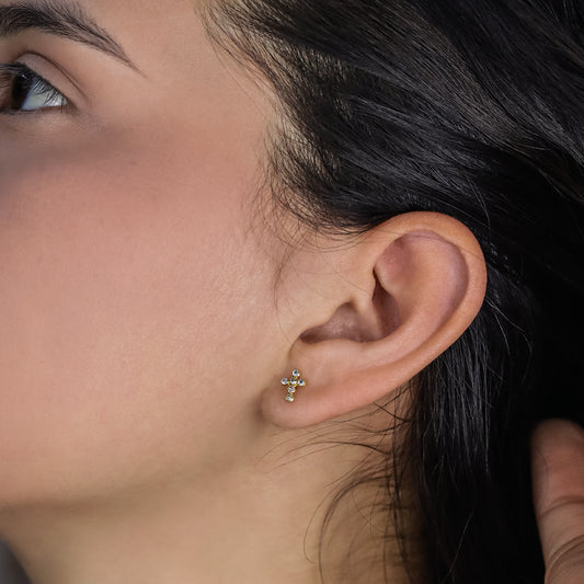 Oreja de mujer con topito en forma de cruz en oro amarillo de 18 quilates con cristales de color blanco, hechos en Joyería Caracas. 