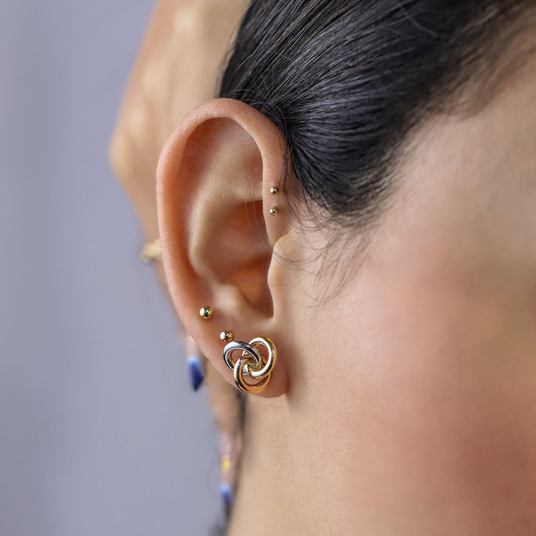 Oreja de mujer con topito en forma de espiral en oro amarillo, blanco y rosa de 18 quilates, hechos en Joyería Caracas. 