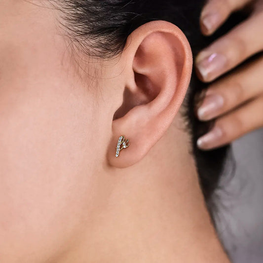 Oreja de mujer con topito de la palabra Fe en oro amarillo de 18 quilates y cristales de color blanco, hecho en Joyería Caracas. 