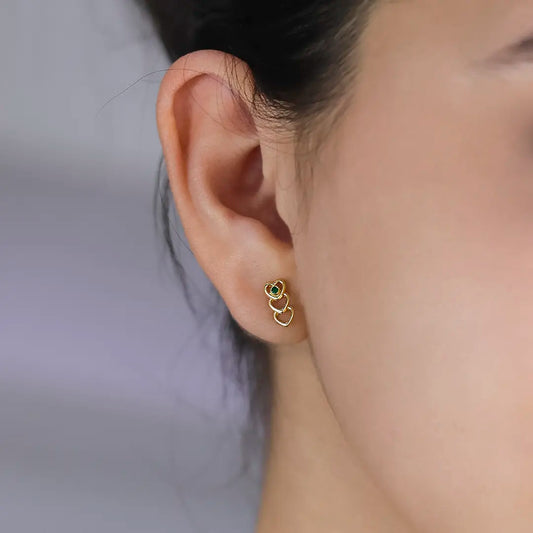 Oreja de mujer con topito en fila de 3 corazones en oro amarillo de 18 quilates y cristal de color verde, hecho en Joyería Caracas. 