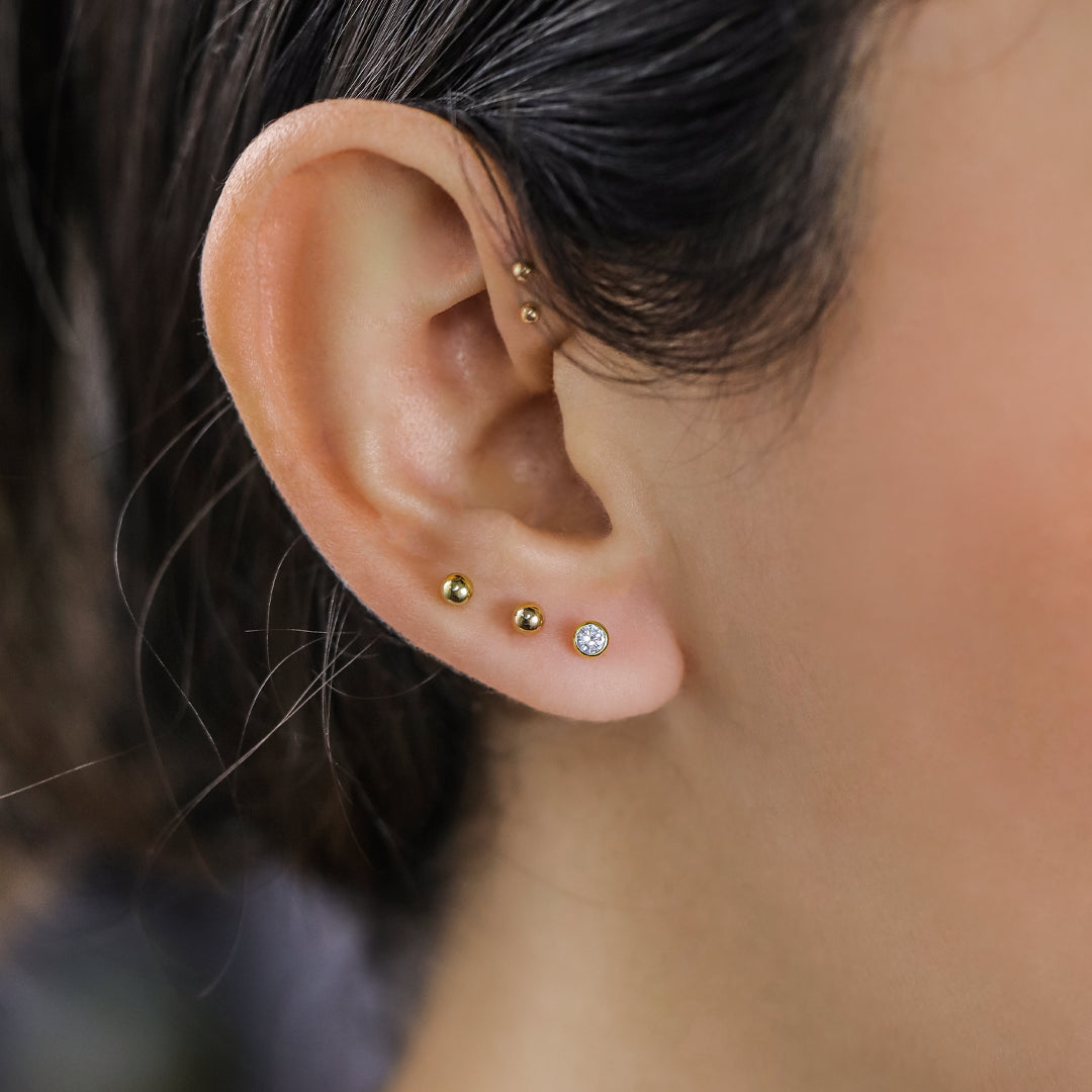 Oreja de mujer con topito Gema biselada en oro amarillo de 18 quilates y cristal de color blanco, hechos en Joyería Caracas. 