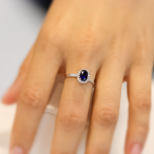 Mano de mujer con anillo en oro blanco de 18 quilates con cristal de color azul y blanco, hecho en Joyería Caracas. 