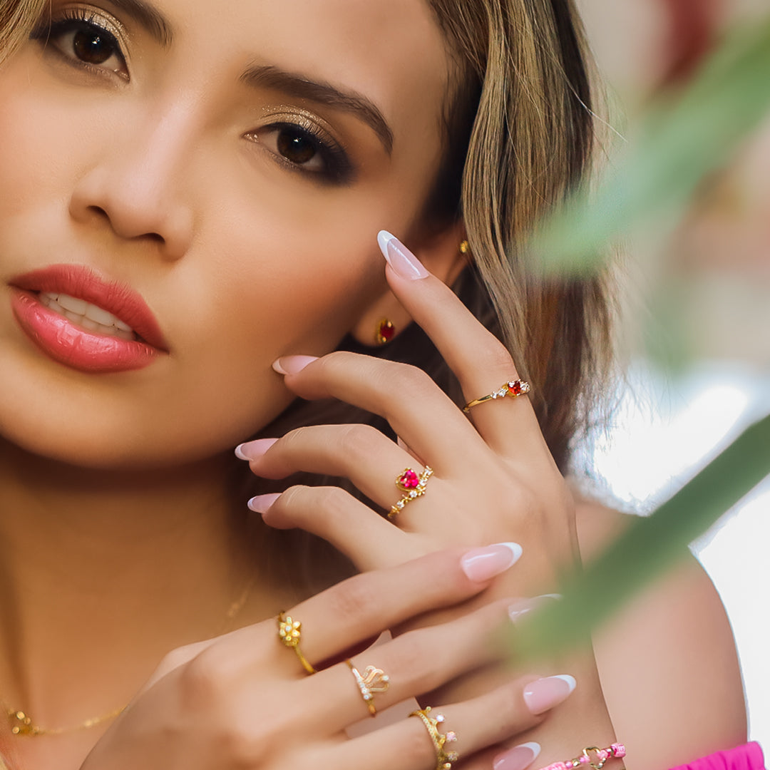 Mano de mujer usando anillo en oro amarillo de 18 quilates con cristal en forma de corazón de color rojo y cristales de color blanco, hecho en Joyería Caracas. 