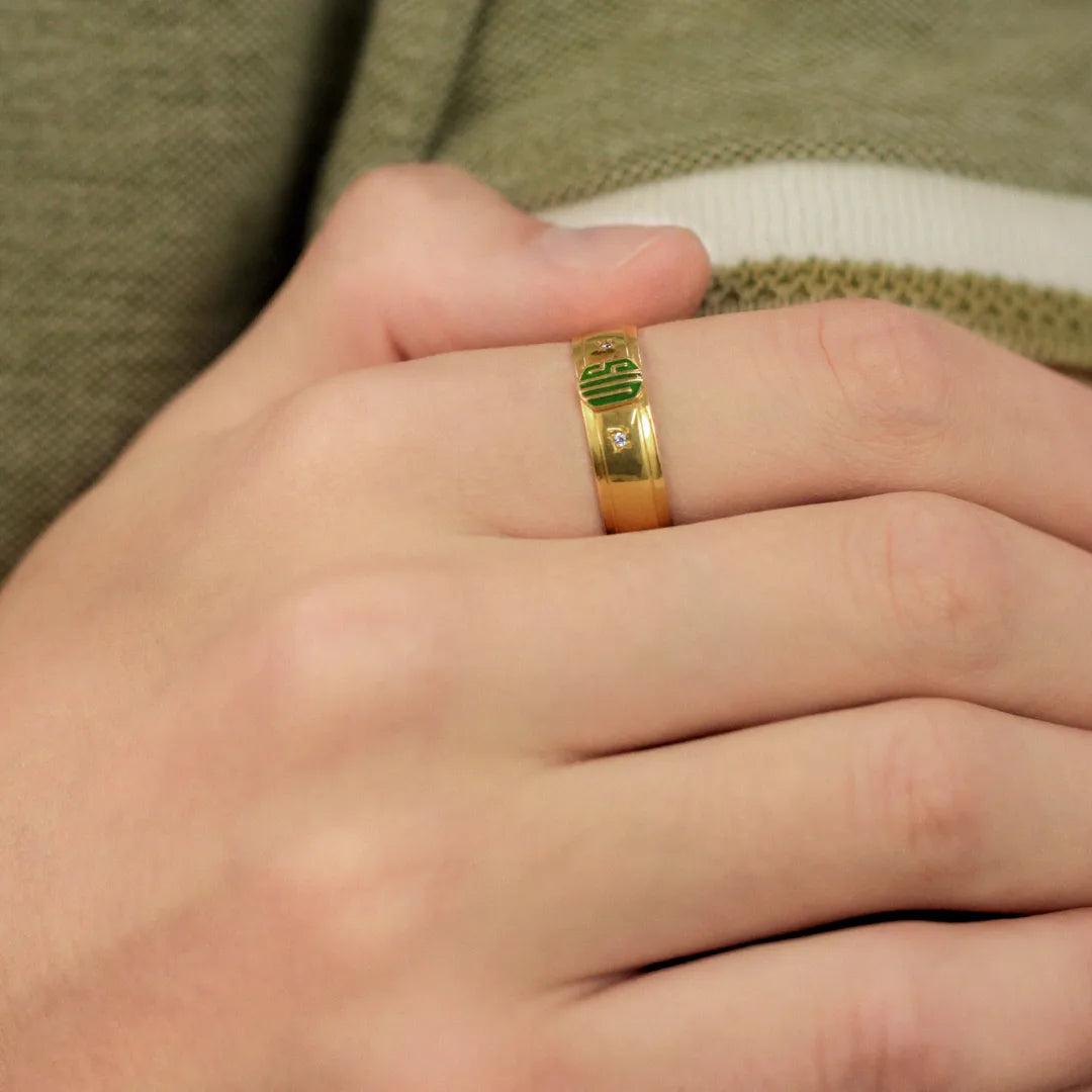 Mano con anillo de grado hecho en oro de 18k, color amarillo, el cual contiene 2 cristales, ubicado en el dedo índice.