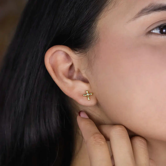 Oreja de mujer con topito en forma de cruz en oro amarillo de 18 quilates con cristal de color blanco en el centro, hechos en Joyería Caracas. 