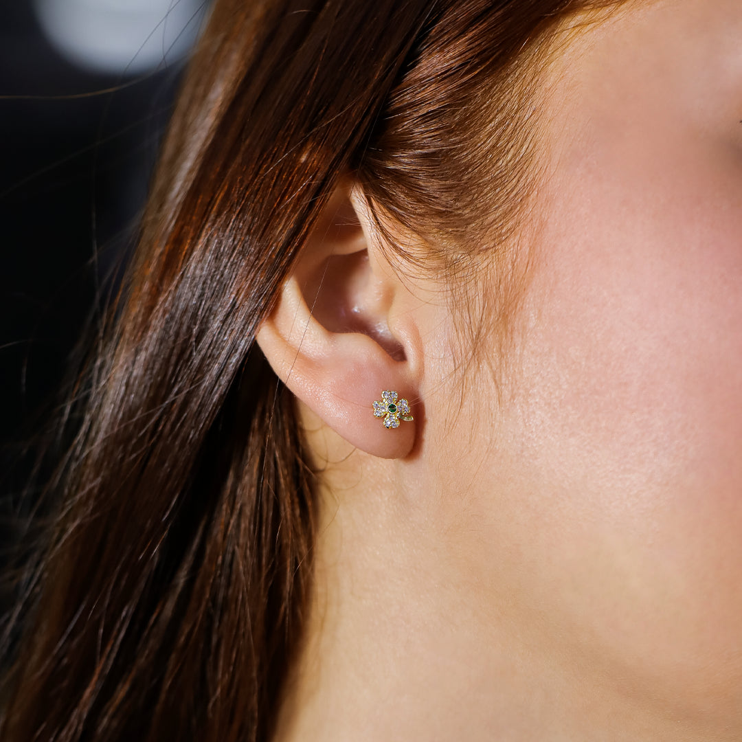 Oreja de mujer con topito en forma de trébol en oro amarillo de 18 quilates con cristales de color blanco y verde, hecho en Joyería Caracas.  