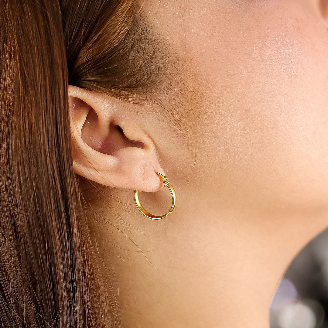 Oreja de mujer con candongas de media caña lisa en oro amarillo de 18 quilates de Joyería Caracas. 