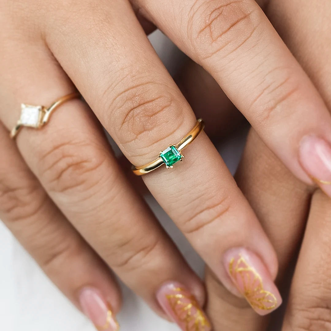 Mano de mujer con anillo en oro amarillo de 18 quilates con piedra preciosa de esmeralda, hecho en Joyería Caracas. 