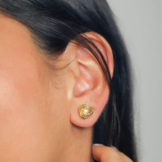 Oreja de mujer con topito en forma de espiral en oro amarillo de 18 quilates con cristal de color blanco en el centro, hechos en Joyería Caracas. 