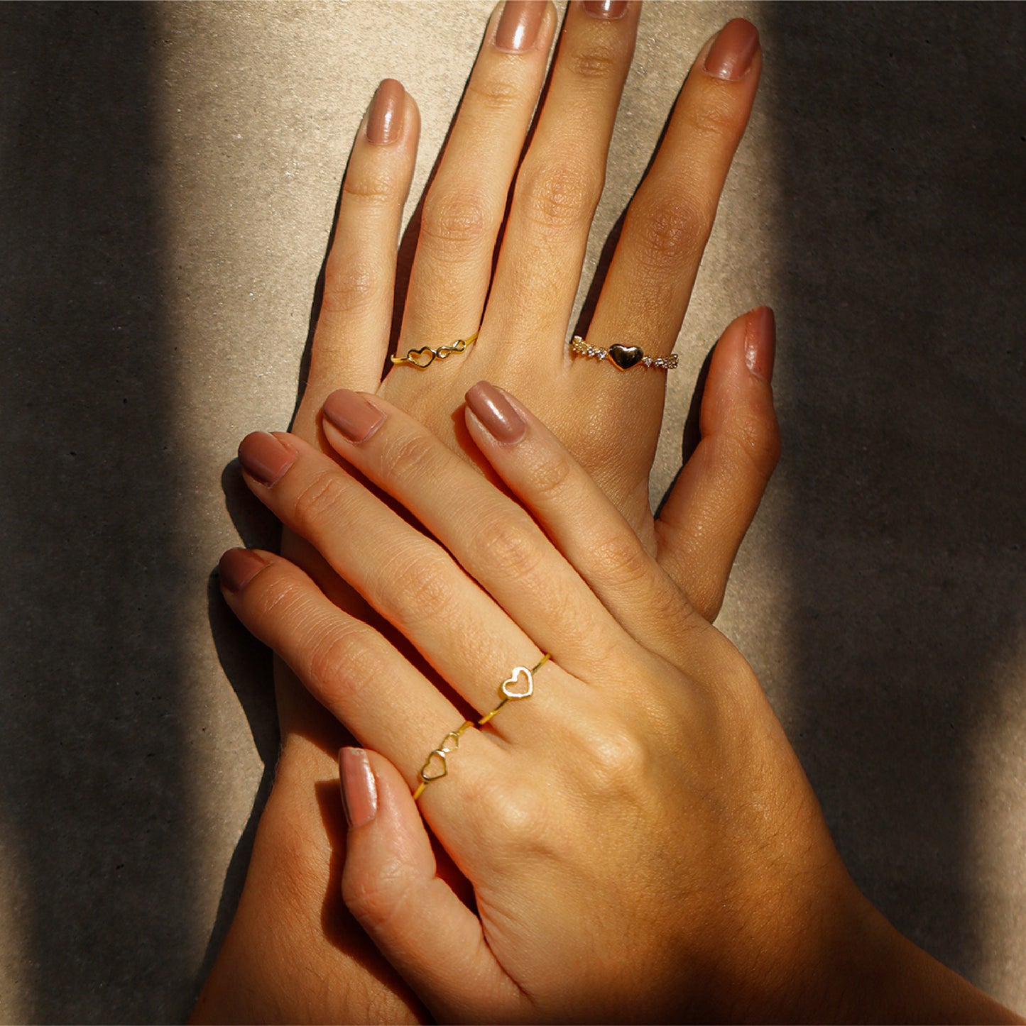 Mano de mujer con anillo en forma de corazón e infinito en oro amarillo de 18 quilates, hecho en Joyería Caracas. 