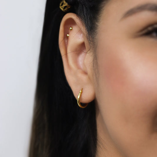 Oreja de modelo con una candonga de tubo pequeña de oro 18k.