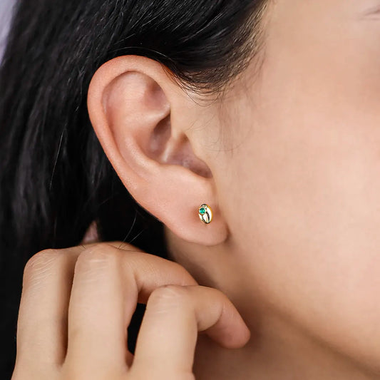 Oreja de mujer con topito en forma de grano de café con cristal de color verde, hecho en joyeria caracas. 