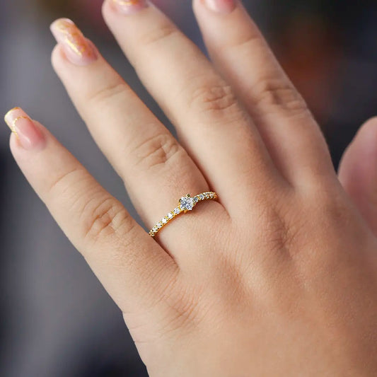 Mano de mujer con anillo en oro amarillo de 18 quilates con cristales de color blanco alrededor y uno en forma de rombo en el centro, hecho en Joyería Caracas. 